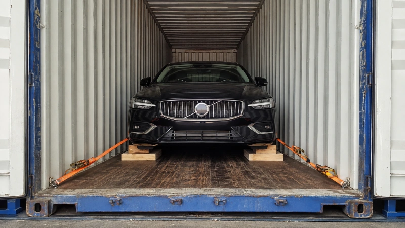 Passenger car professionally secured inside a shipping container with wheel chocks and rated lashings