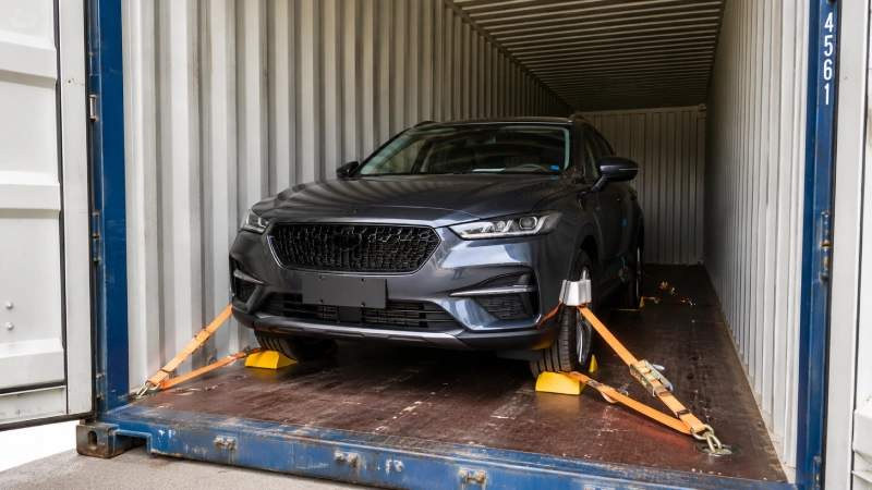 Passenger car secured with wheel restraints and lashing straps inside a shipping container